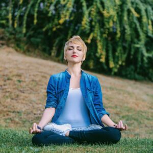 Woman practicing mindful breathing in a serene natural setting, embodying the principles of Integrative Somatic Therapy.