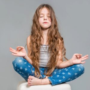 Emotional Neglect in Childhood – Inner Child Healing and Emotional Safety - Somatic Therapy Ireland Child sitting cross-legged with eyes closed in a calm meditative pose, symbolising emotional neglect in childhood and the inner child’s need for safety, presence, and emotional attunement.