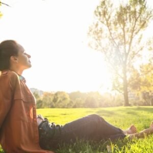 Woman sitting outdoors in a natural setting, looking out at the surroundings